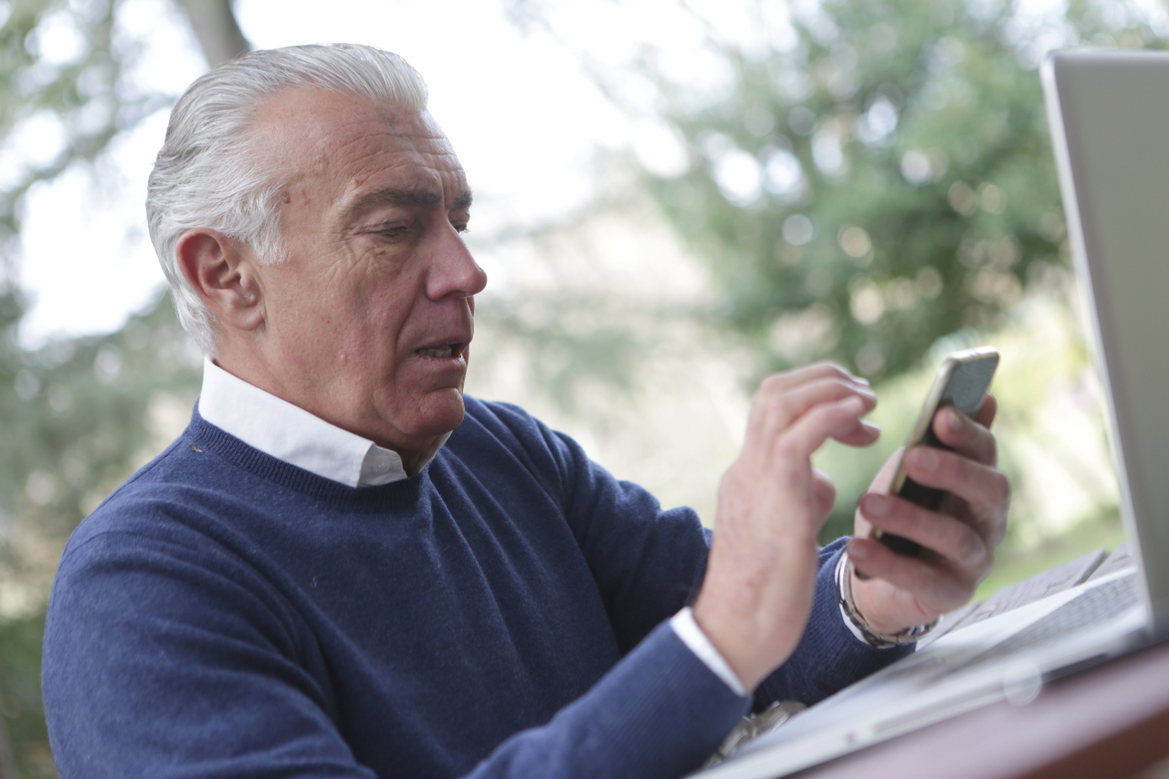 Elderly man holding a mobile phone.