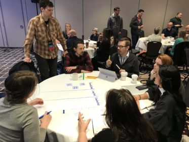 A photo from a workshop about enterprise product design. Several conference-goers collaborate on an activity guides by a Blink's Chief Design Officer, Geoff Harrison