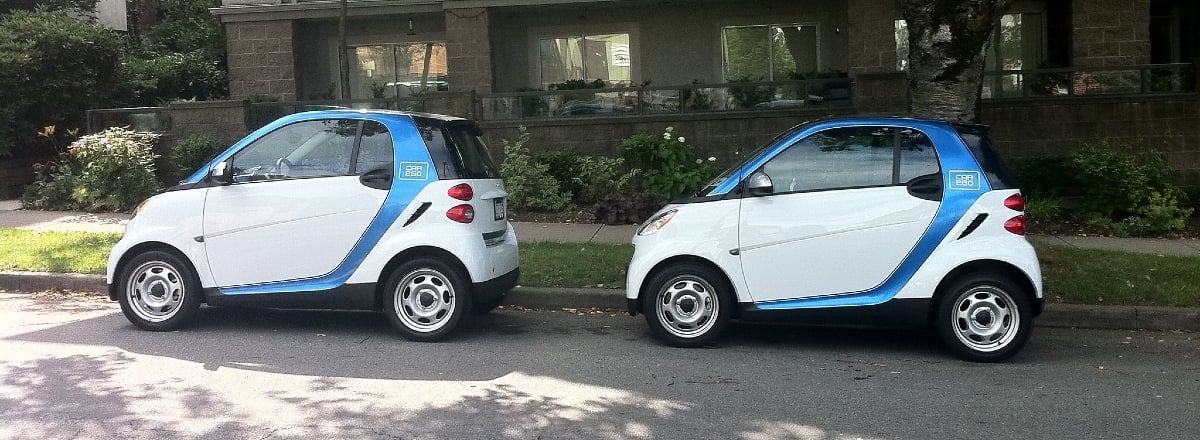 Two white and blue smart cars parked on the side of a street