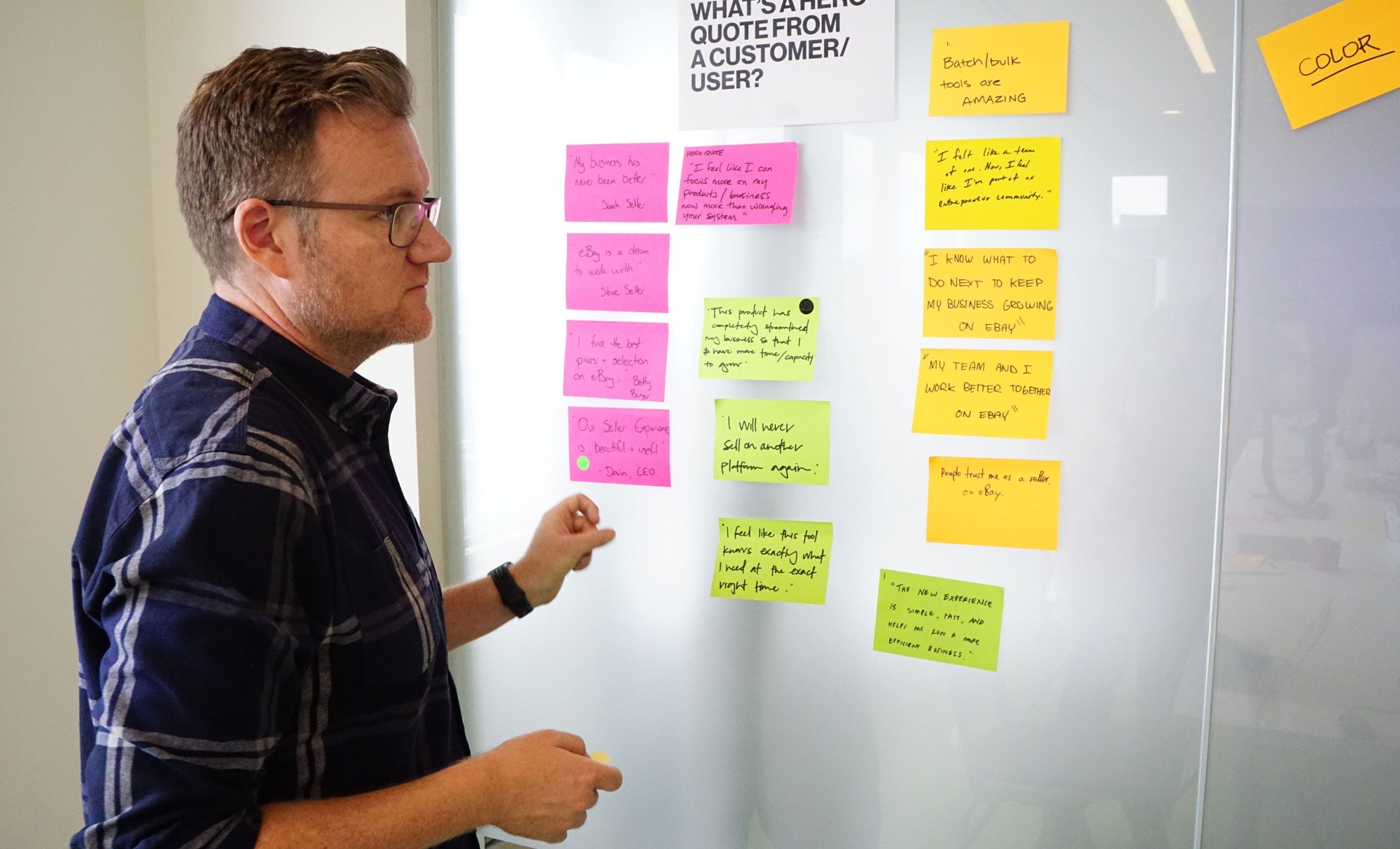 Man at plaid shirt looking at stickie notes on a whiteboard