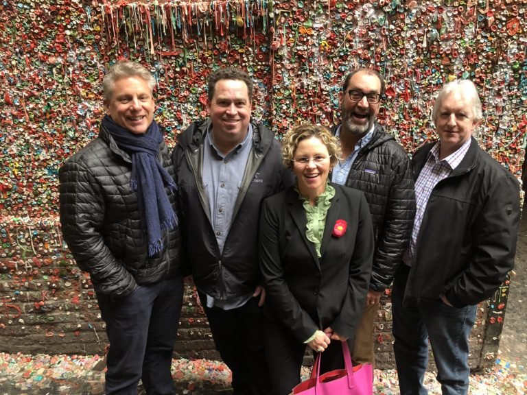 Blink leaders posing in front of a wall covered in gum