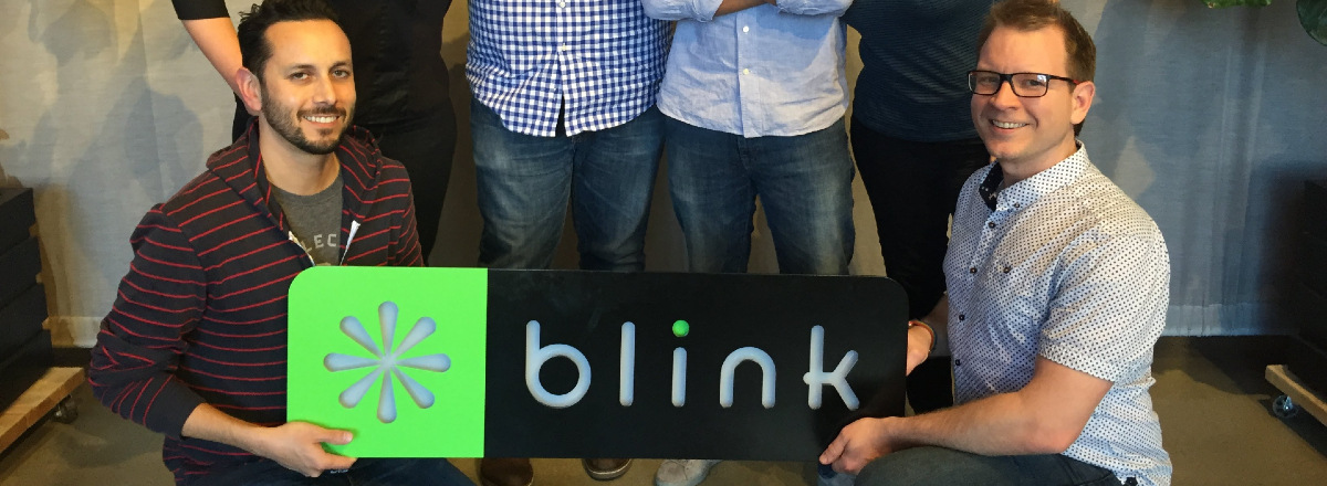 Blink team members posing holding a Blink logo sign