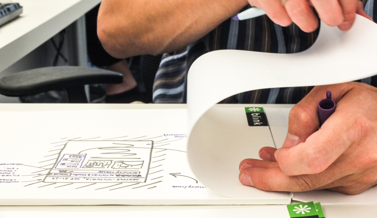 Male hands folding back a piece of paper on a blink logo drawing pad
