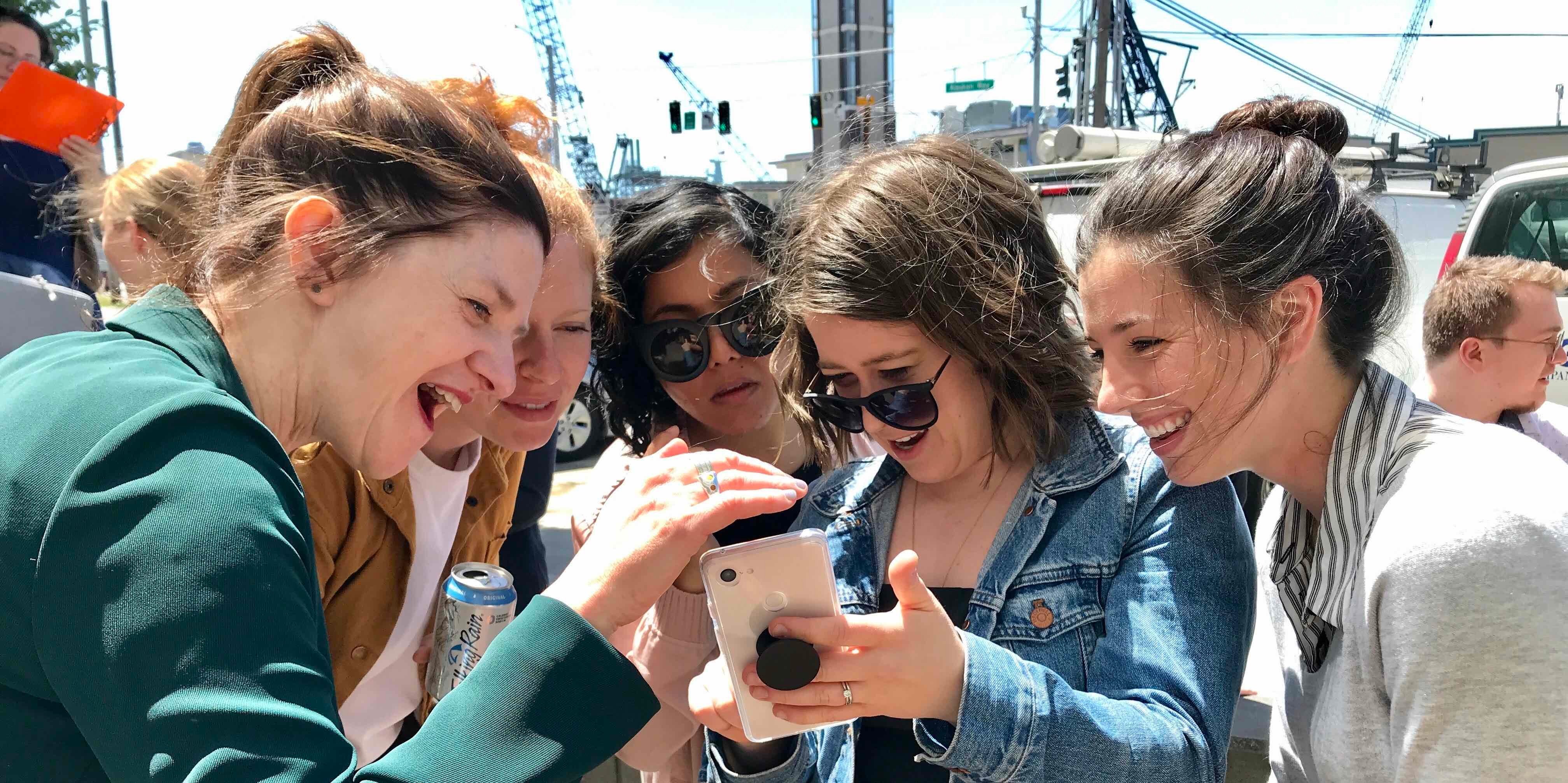 Blink team members looking at a phone during a sunny day in Seattle.