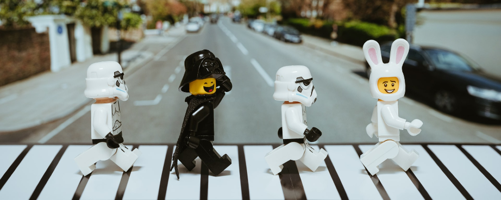 Darth Vader and stormtrooper Lego figures crossing a crosswalk.
