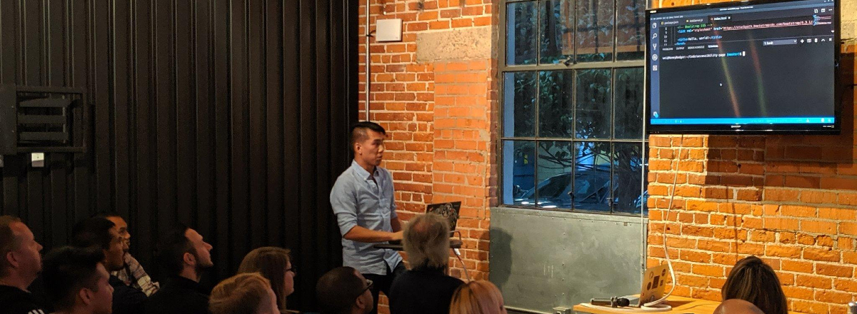Man discussing a snippet of code in front of a crowd.