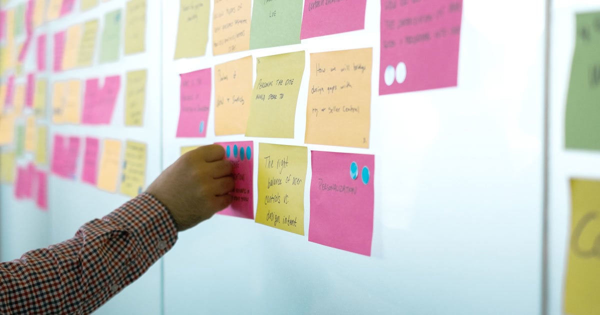 A person places dot stickers on post-it notes as part of our Speak Your Mind activity.