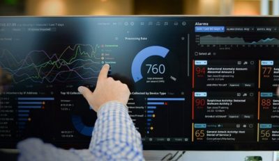 A photo of a person pointing to the dashboard information panel for an enterprise software application.