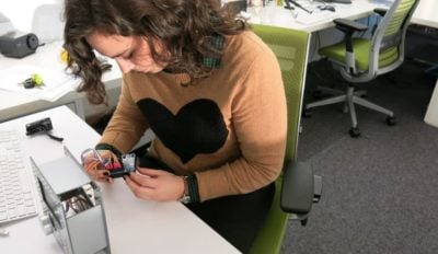 A photo of a person at a worktable examining a piece of computer hardware.