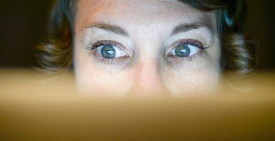 A photograph of a woman looking at her computer