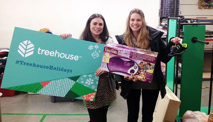 Two people holding donations for the Treehouse nonprofit charity.
