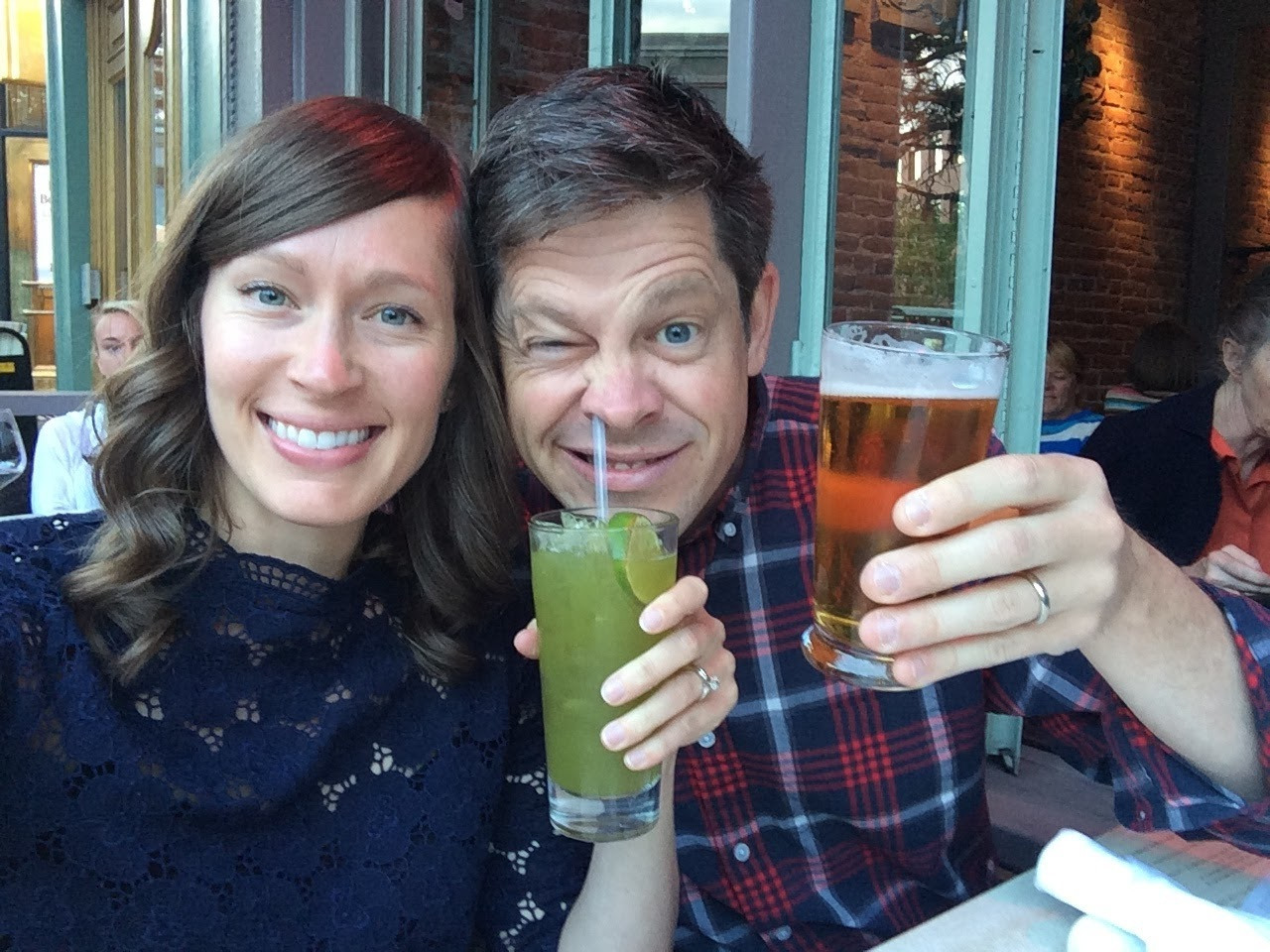 Two people holding drinks and smiling at the camera.